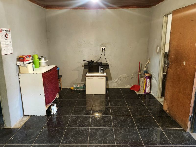 A basic kitchen area featuring dark tiled flooring and a timber ceiling, currently requiring maintenance and cosmetic updates to the walls and finishes.