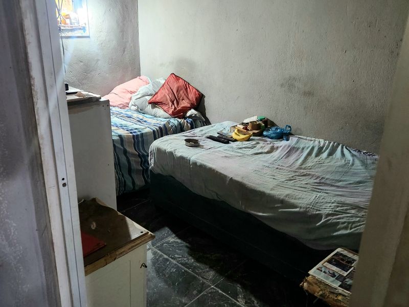 A compact bedroom featuring tiled flooring and unfinished wall surfaces, requiring cosmetic updates to improve the overall aesthetic and finish.