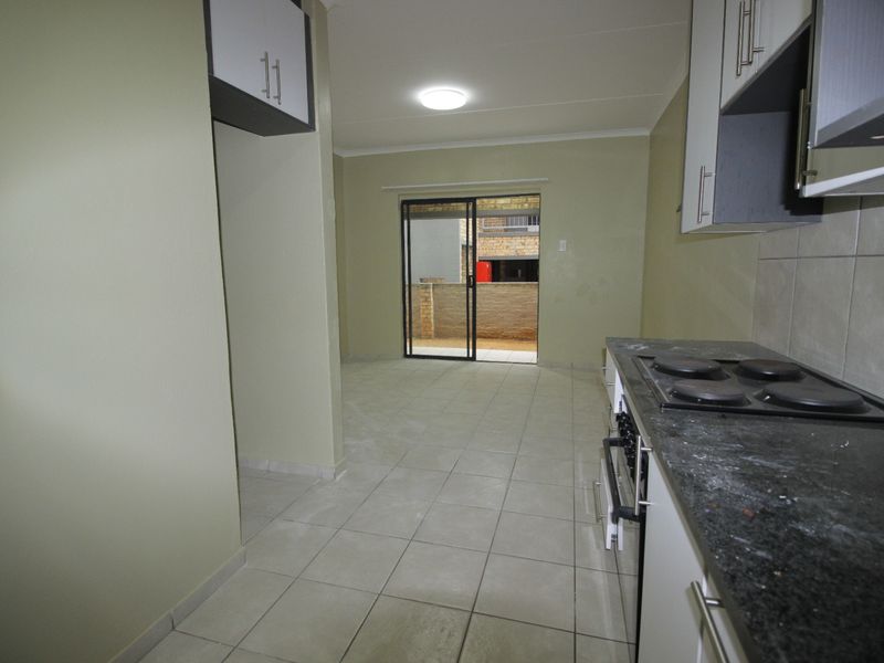 Open-plan kitchen and living area featuring tiled floors, built-in cabinetry with an integrated oven and hob, and sliding door access to the exterior.
