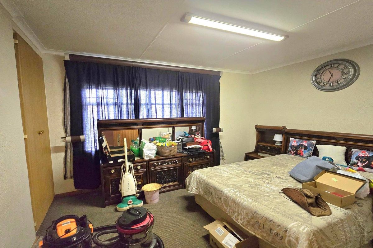 A standard bedroom featuring carpeted flooring, a built-in cupboard, and a fluorescent ceiling light fixture.