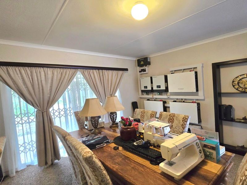 Living area featuring a wall-mounted solar inverter and battery storage system, with sliding glass doors leading to the exterior.