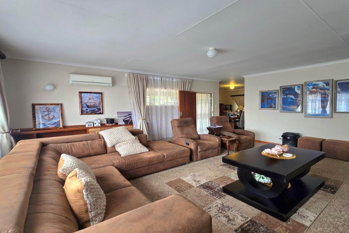 Spacious living room featuring carpeted flooring, a wall-mounted air conditioning unit, and neutral wall finishes.