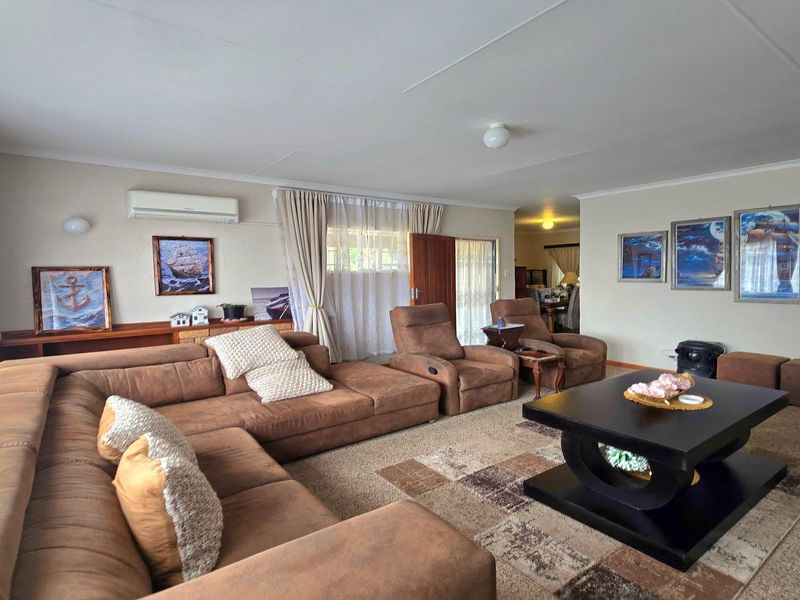 Spacious living room featuring carpeted flooring, a wall-mounted air conditioning unit, and neutral wall finishes.