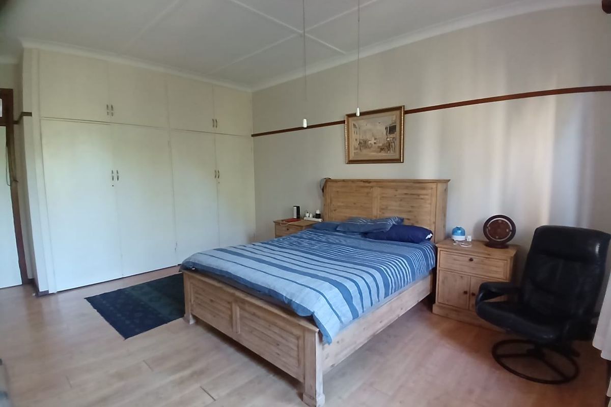 Spacious bedroom featuring light laminate flooring, neutral walls, and extensive built-in cupboard storage.