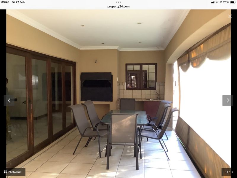Covered patio area featuring a built-in braai, sink, and tiled flooring, providing a functional space for outdoor dining and entertainment.