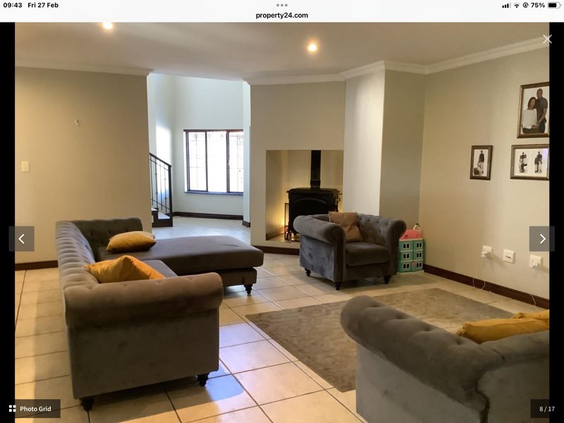Spacious living room featuring tiled flooring, a central freestanding fireplace, and recessed lighting, with an open-plan layout leading to a staircase.