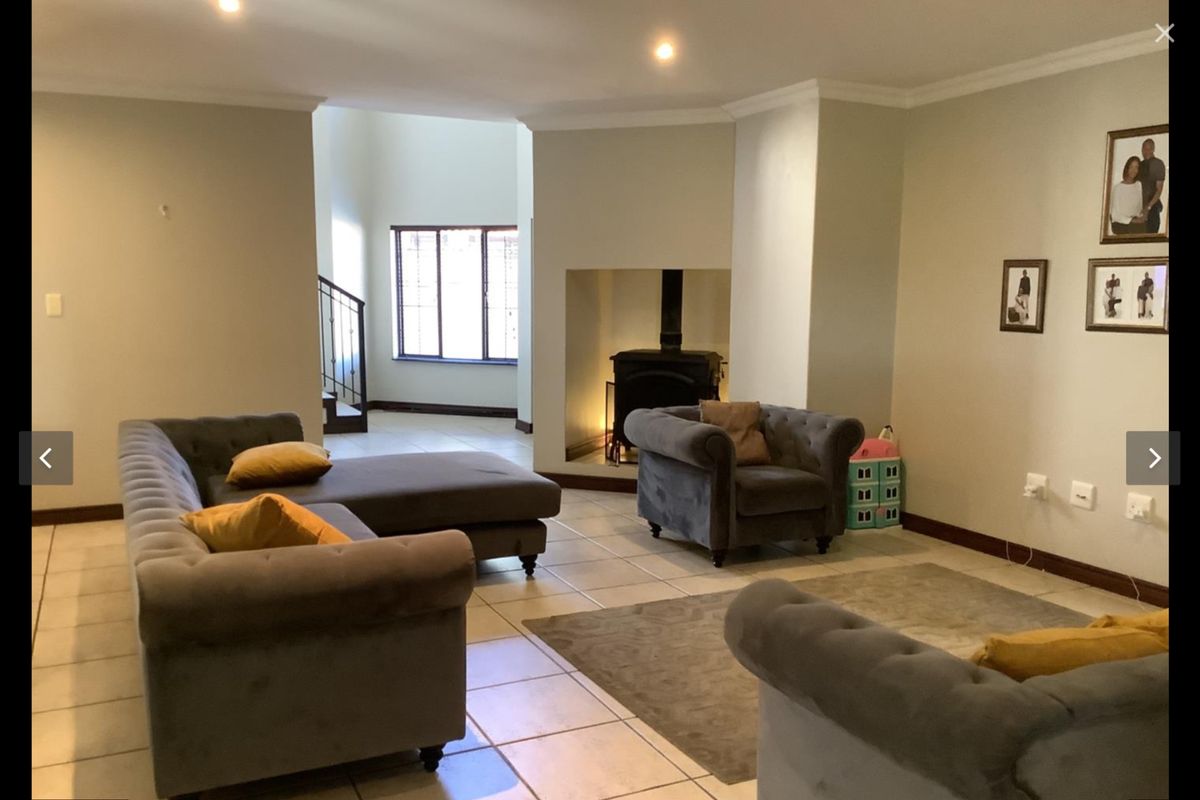 Spacious living room featuring tiled flooring, a central freestanding fireplace, and recessed lighting, with an open-plan layout leading to a staircase.