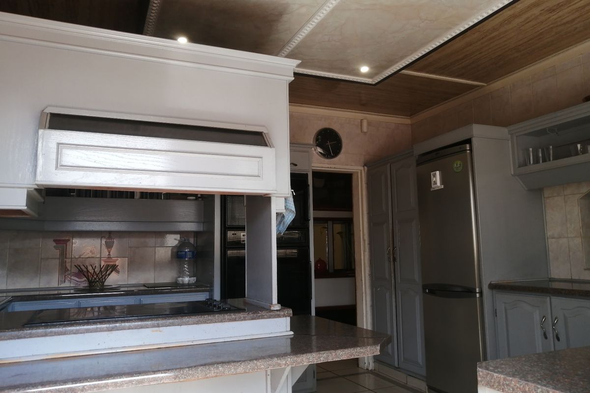 A functional kitchen featuring built-in cabinetry, stone countertops, integrated oven, and a tiled backsplash with recessed ceiling lighting.