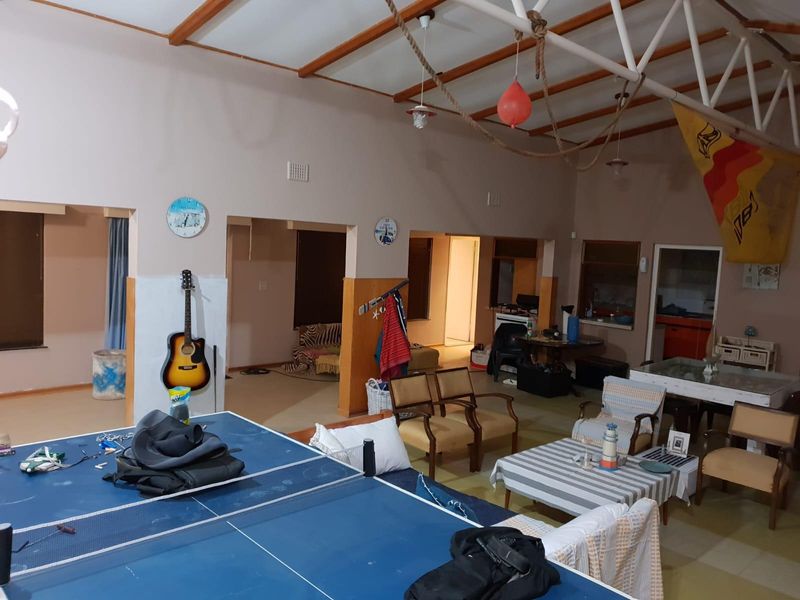 Spacious open-plan living area featuring exposed roof trusses and tiled flooring, offering versatile layout potential for a large family or entertainment space.