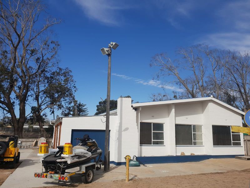 Front exterior view of a single-story masonry house featuring a driveway, garage, and prominent floodlight pole.