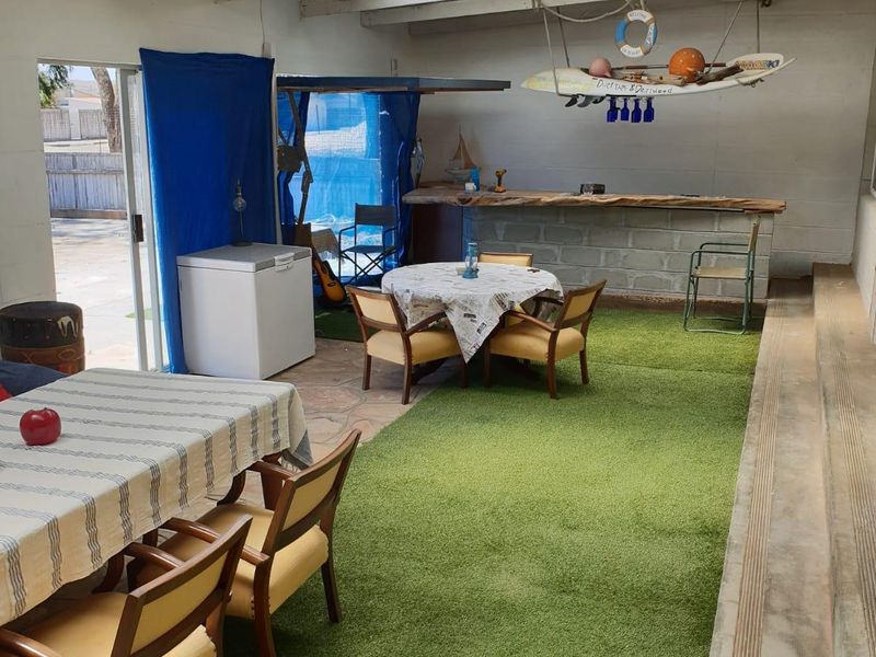 Covered outdoor patio area featuring a built-in masonry bar, translucent roof panels, and direct access to the rear yard via sliding glass doors.