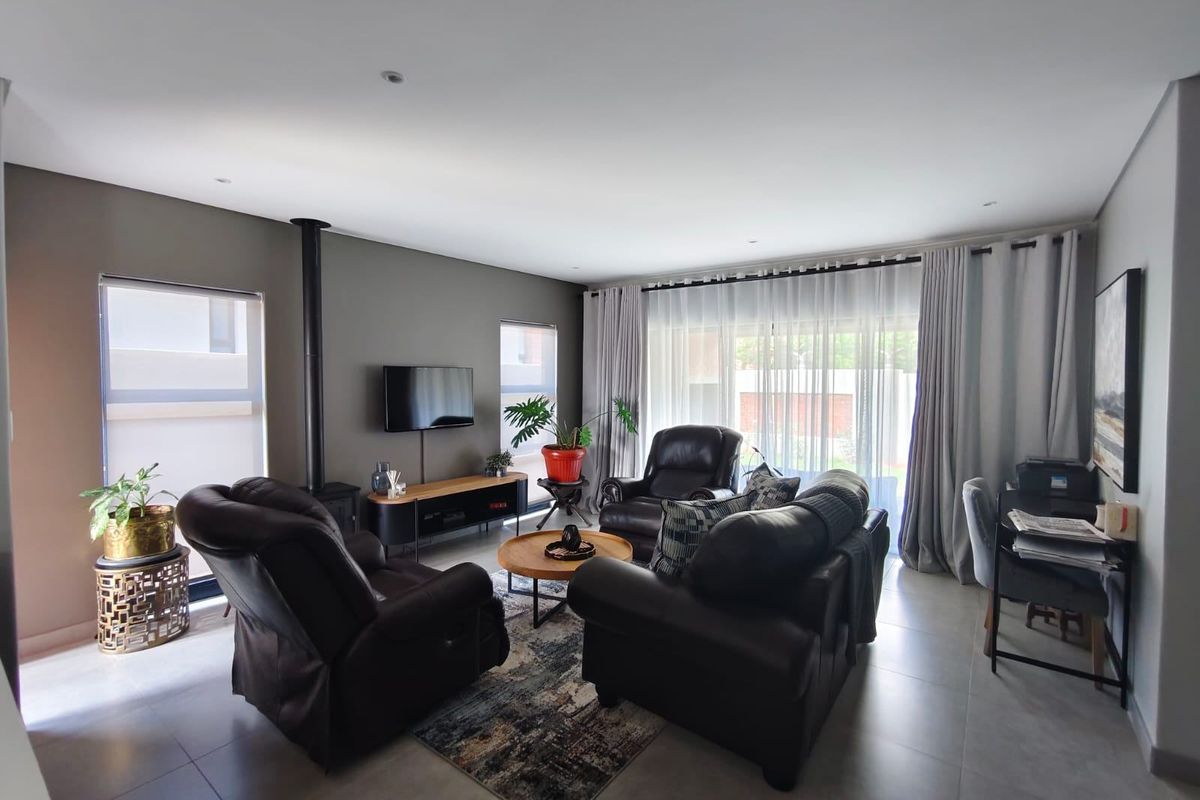 Spacious living room featuring large format floor tiles, a modern freestanding fireplace, and sliding glass doors providing access to the outdoor area.
