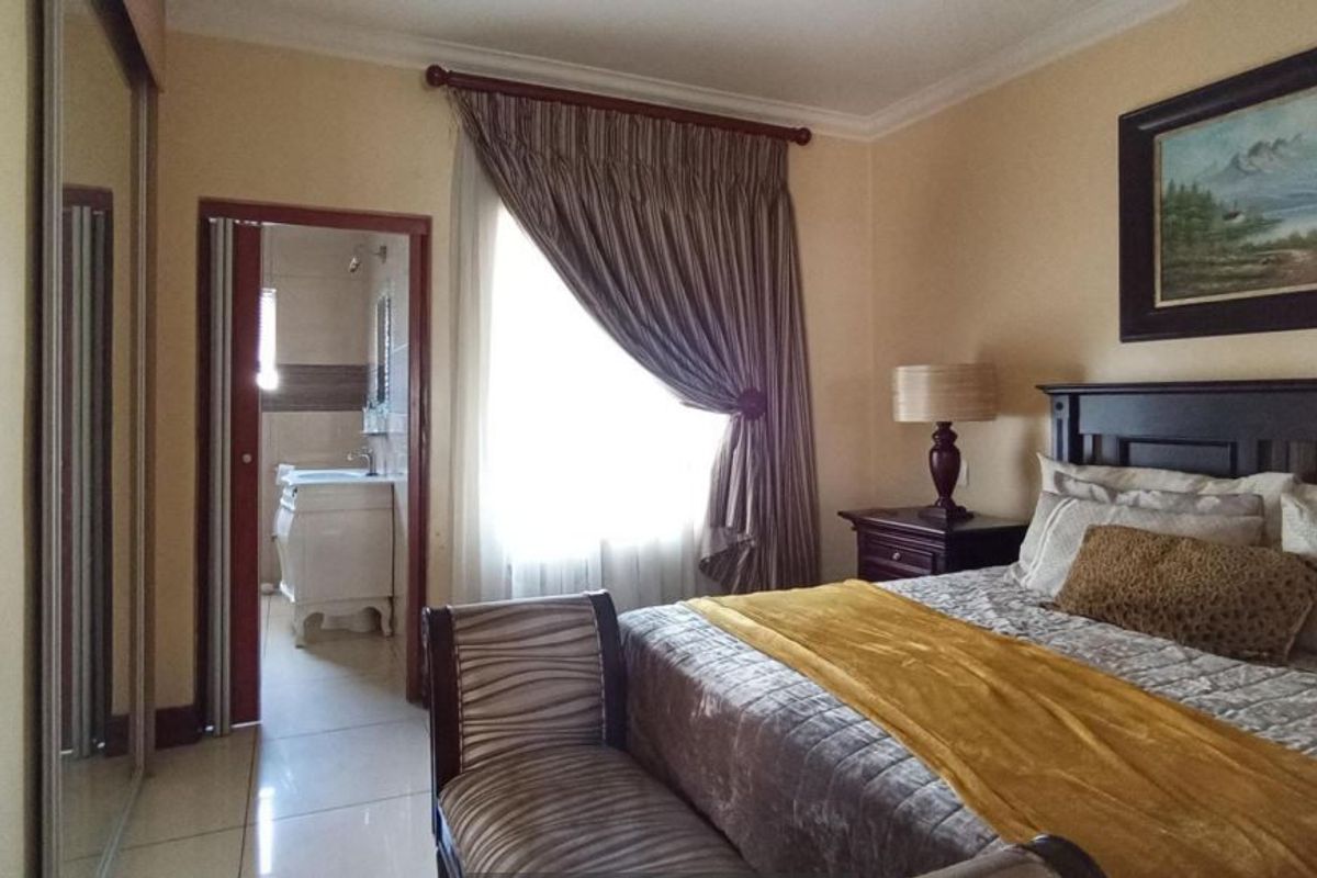 A well-maintained bedroom featuring tiled flooring, a built-in wardrobe, and direct access to an en-suite bathroom.