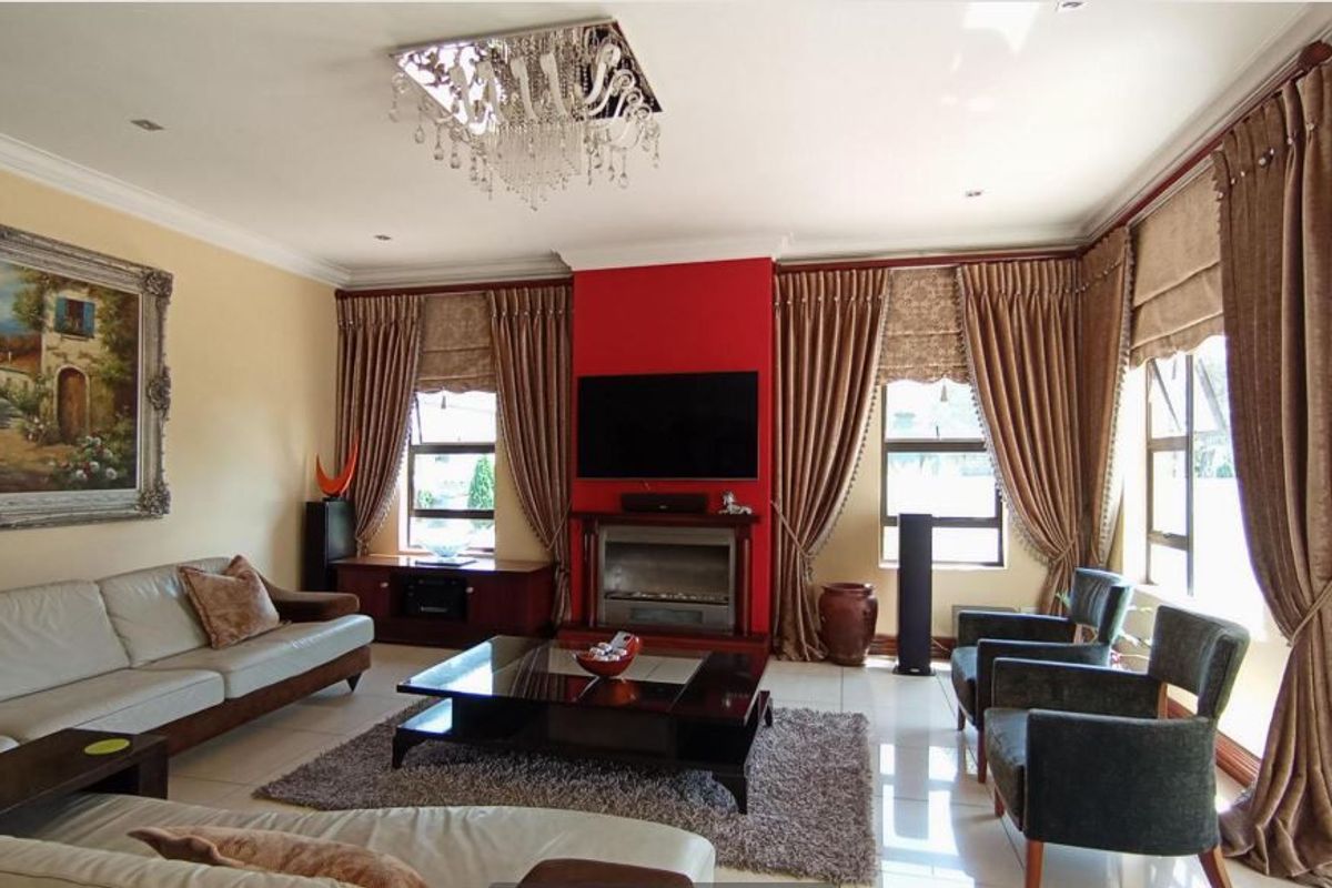Spacious living room featuring a central fireplace, tiled flooring, crown molding, and recessed lighting, creating a comfortable and well-defined entertainment area.