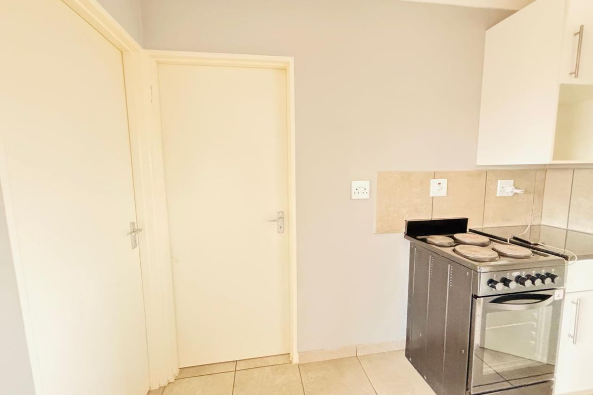 A functional kitchen area featuring tiled flooring, a tiled backsplash, and built-in cabinetry with a freestanding stove.