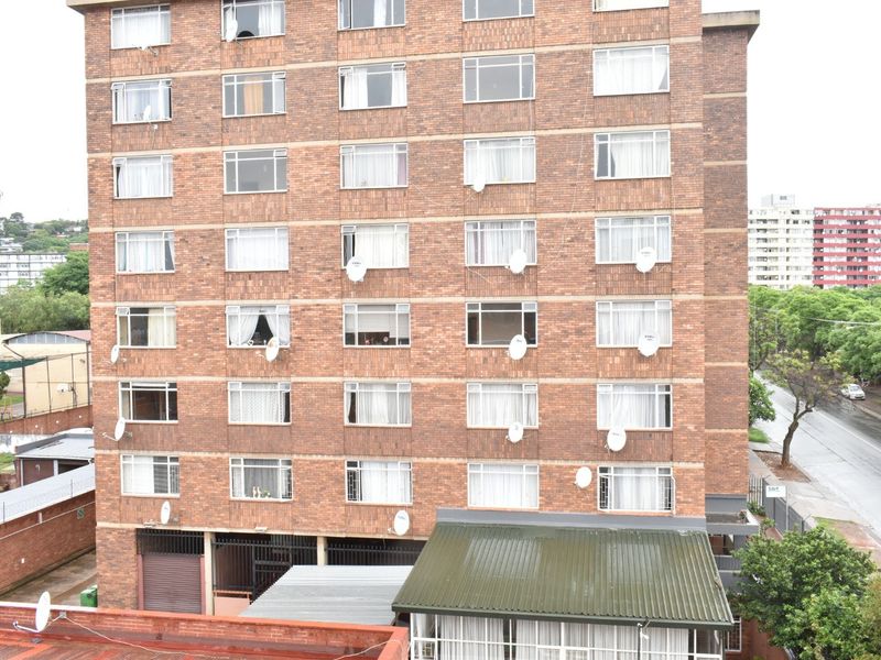 Exterior view of a multi-story brick apartment building featuring multiple windows and installed satellite dishes.