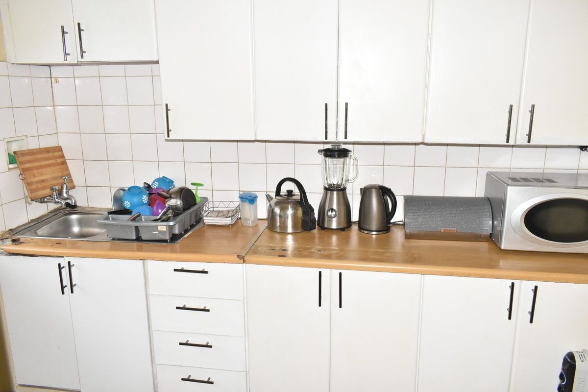 A functional kitchen featuring white cabinetry, a laminate countertop, and a tiled backsplash, providing a practical workspace for daily meal preparation.