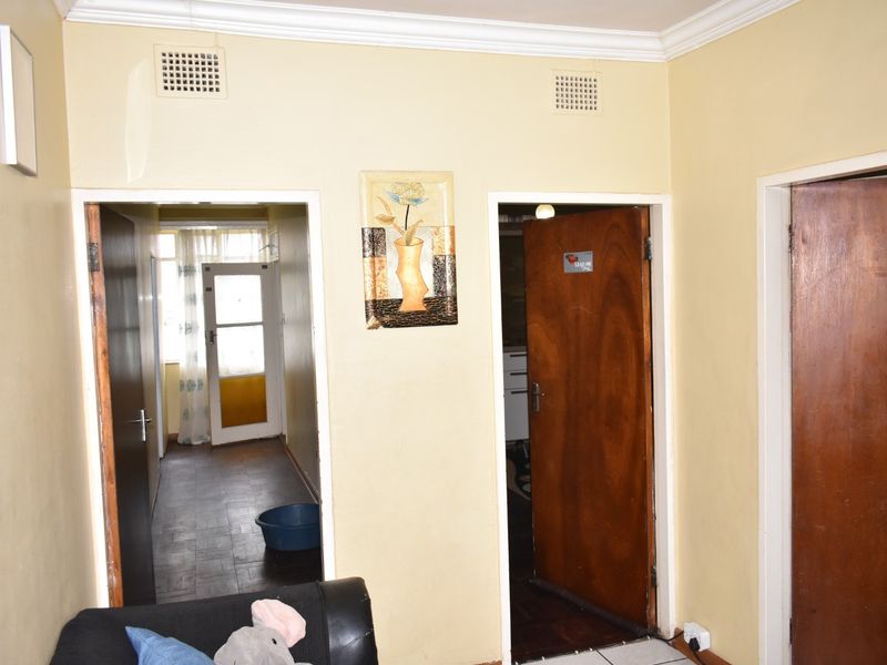 A functional hallway area featuring multiple timber doors, decorative cornice, and ventilation grilles, providing access to adjacent rooms within the apartment.
