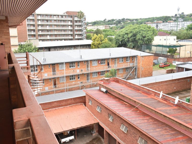 Elevated view overlooking the apartment complex, featuring brick building facades, metal roofing, and an external spiral staircase.