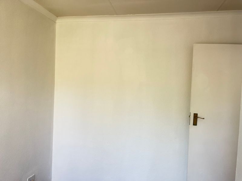 A simple, empty bedroom featuring white walls, coving, and a standard internal door.
