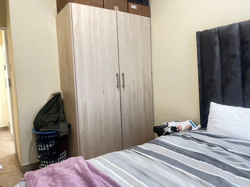 A bedroom featuring a light wood-finish built-in wardrobe and neutral wall finishes.
