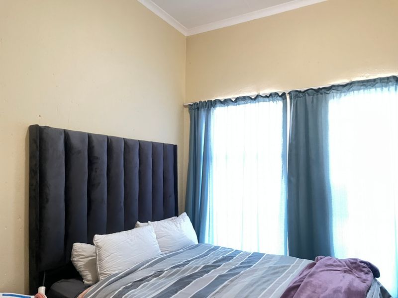 A bedroom featuring neutral wall finishes and natural light through window treatments.