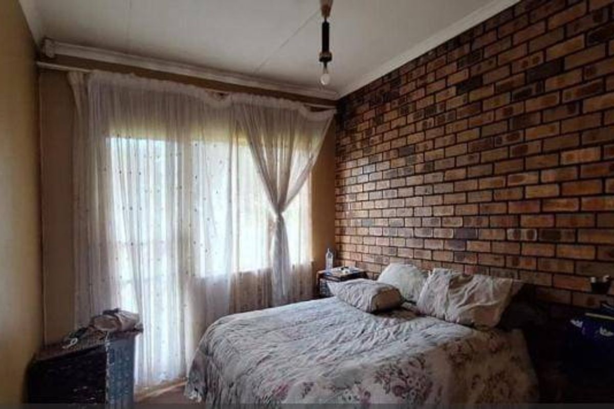 A bedroom featuring an exposed brick feature wall and a sliding glass door providing natural light.
