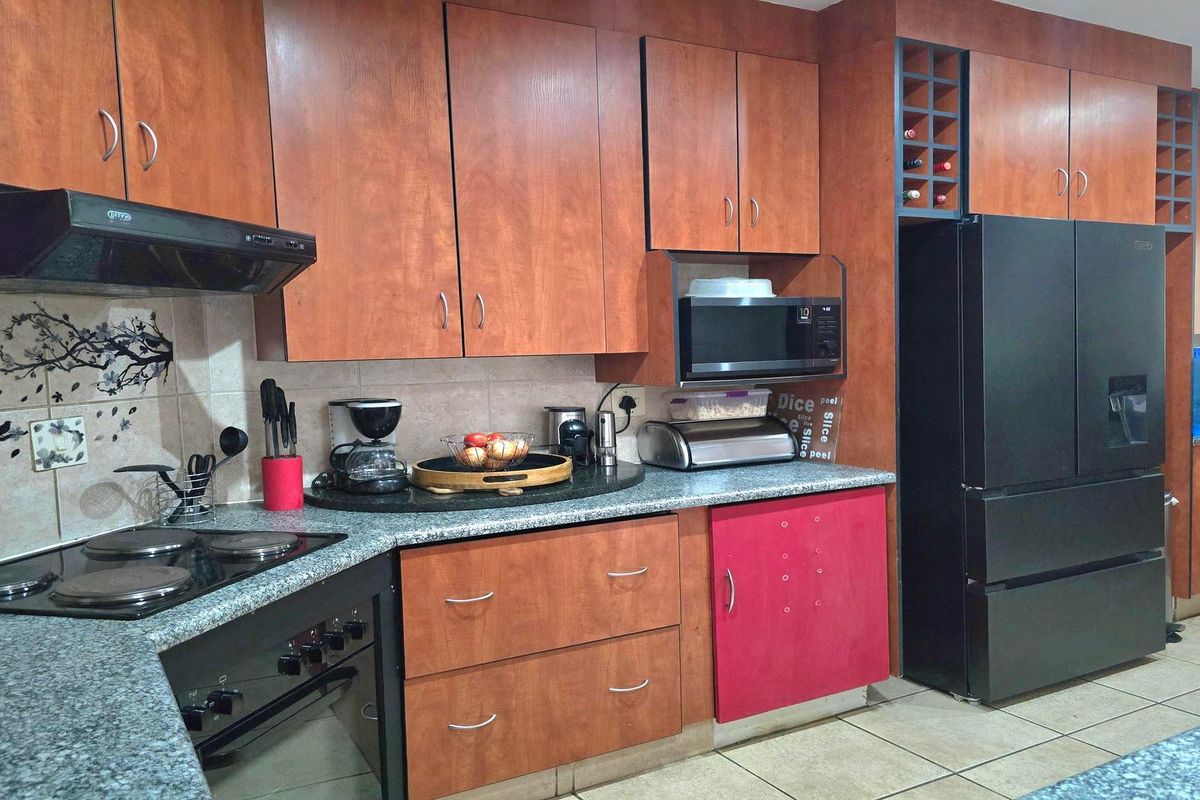 A functional kitchen featuring wood-finish cabinetry, granite countertops, integrated appliances, and a dedicated wine rack, offering ample storage and workspace.