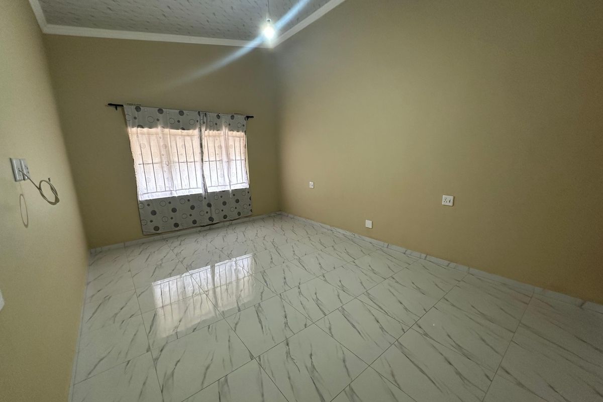 An empty bedroom featuring marble-look floor tiles, a textured ceiling, and neutral wall paint, providing a blank canvas for personalization.