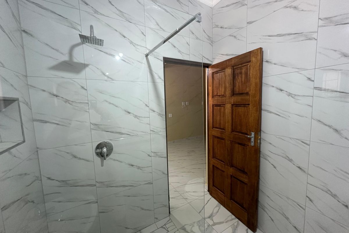 Modern bathroom featuring marble-look wall tiles, a glass shower screen with a rain shower head, and a recessed wall niche.