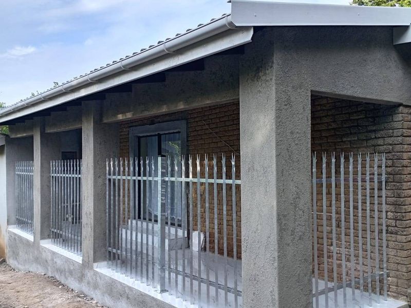 Front exterior view of a house featuring a brick facade, concrete pillars, and installed spiked metal security fencing along the porch area.