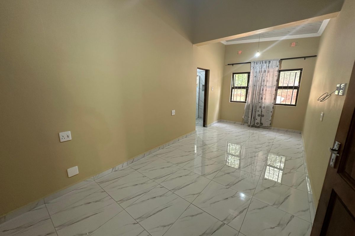 A bright, empty living room featuring modern marble-look floor tiles, high ceilings, and natural light from double-hung windows.