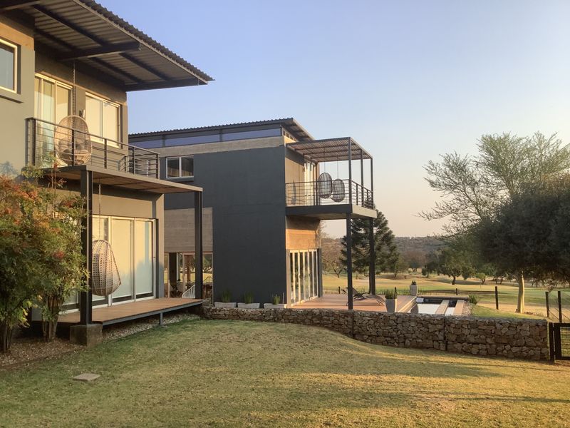 Modern multi-level residence featuring expansive balconies, timber decking, stone retaining walls, and a swimming pool overlooking the surrounding landscape.
