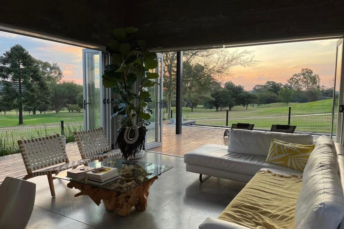 Modern living area featuring polished concrete floors and expansive bi-fold doors opening onto a timber deck with scenic golf course views.
