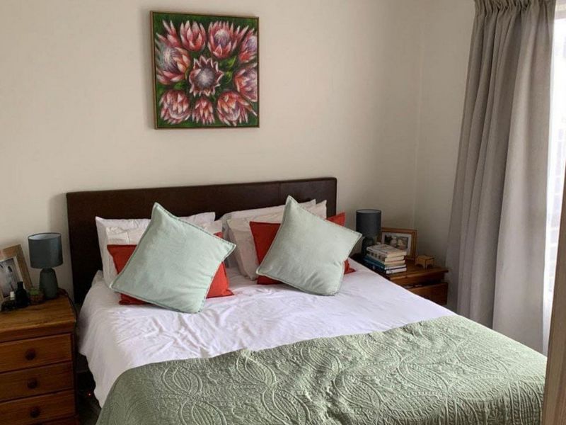 A cozy bedroom featuring neutral walls, tiled flooring, and window treatments, providing a comfortable and functional sleeping space.