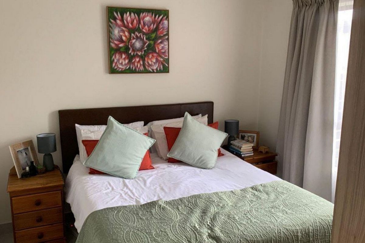 A cozy bedroom featuring neutral walls, tiled flooring, and window treatments, providing a comfortable and functional sleeping space.