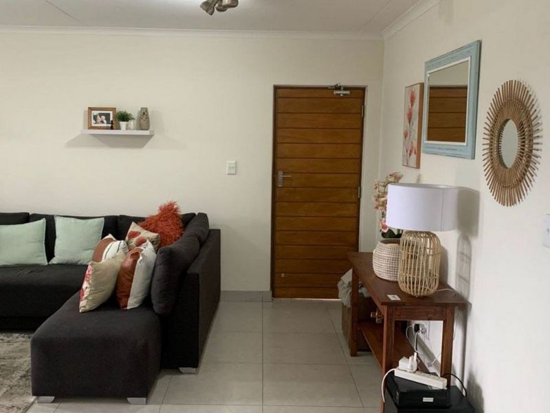 A well-maintained living room featuring neutral tiled flooring and a solid timber entrance door.