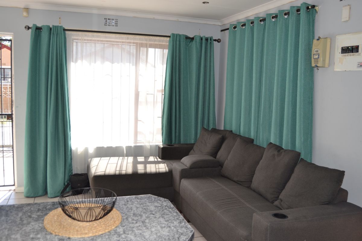 A living room featuring tiled flooring, a sliding door for outdoor access, and an integrated electrical distribution board.