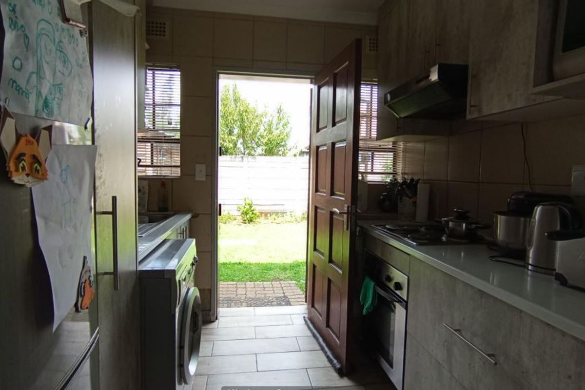Functional kitchen featuring built-in cabinetry, oven, and hob, with direct access to the rear garden area.