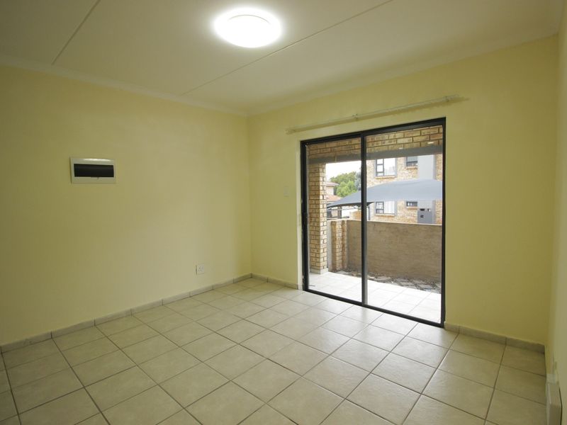 An empty living room featuring tiled flooring and a sliding glass door providing access to an outdoor patio area.