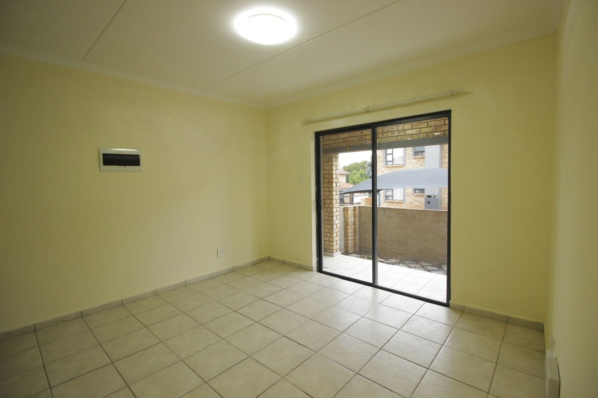An empty living room featuring tiled flooring and a sliding glass door providing access to an outdoor patio area.