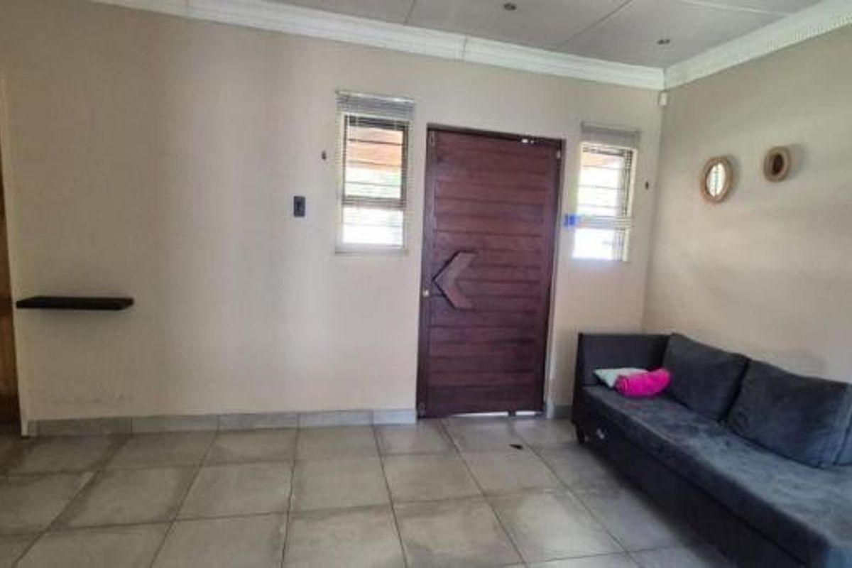 A living room featuring tiled flooring, a solid timber entrance door, and recessed downlights, providing a functional and neutral space.
