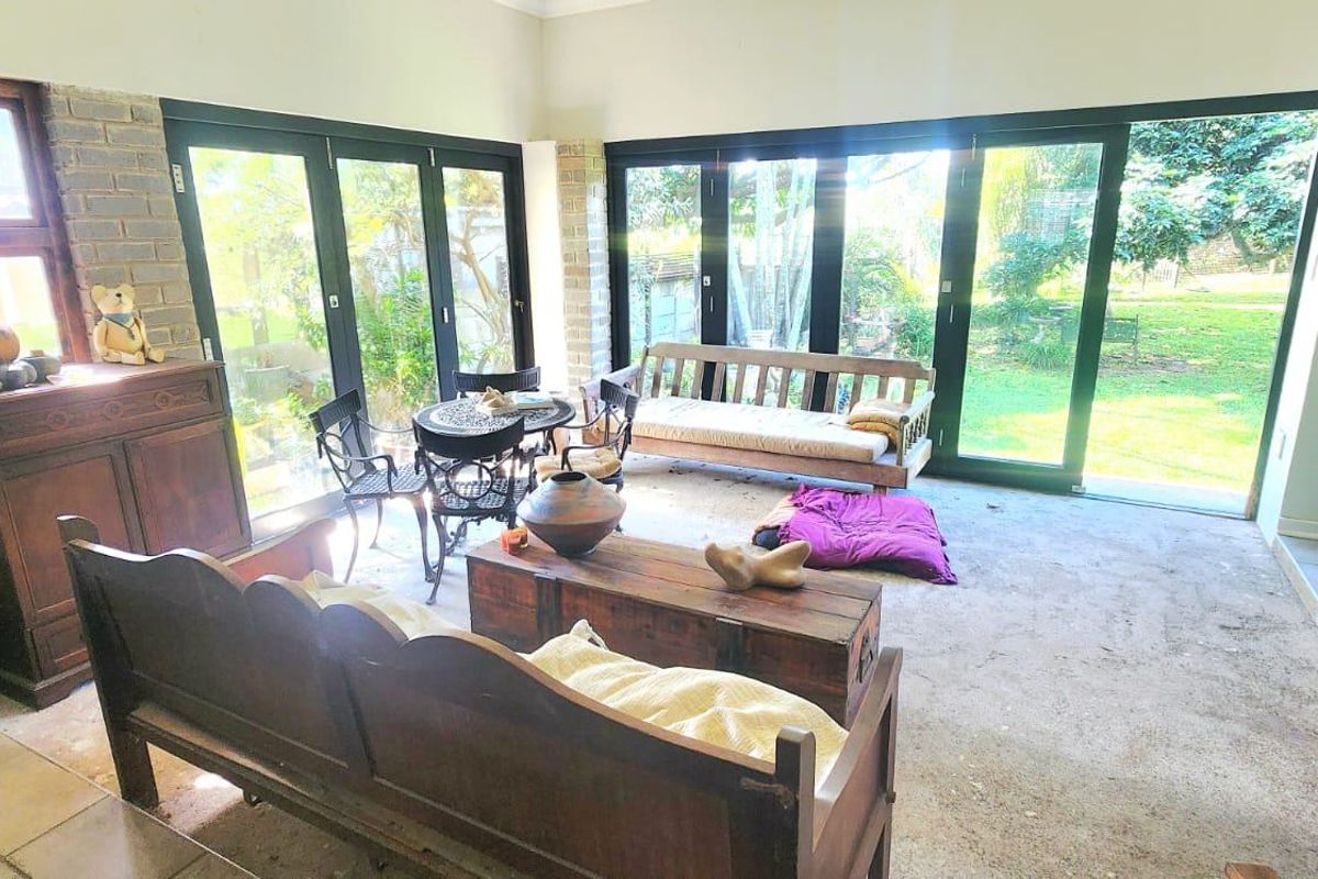 Spacious living area featuring exposed brick walls and large black aluminium stacker doors providing seamless access to the garden.