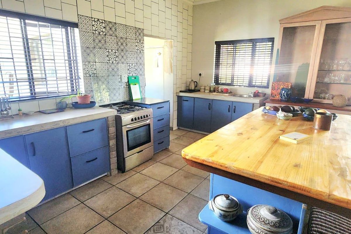 Spacious kitchen featuring blue cabinetry, a central wooden island, gas stove, and tiled backsplash, offering a functional layout with ample counter space.