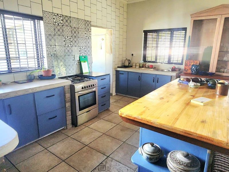Spacious kitchen featuring blue cabinetry, a central wooden island, gas stove, and tiled backsplash, offering a functional layout with ample counter space.