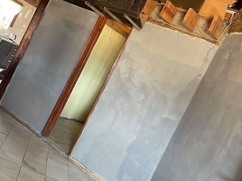 Interior space featuring a traditional thatched roof with exposed timber rafters, ceramic tiled flooring, and unfinished wall surfaces currently undergoing renovation.