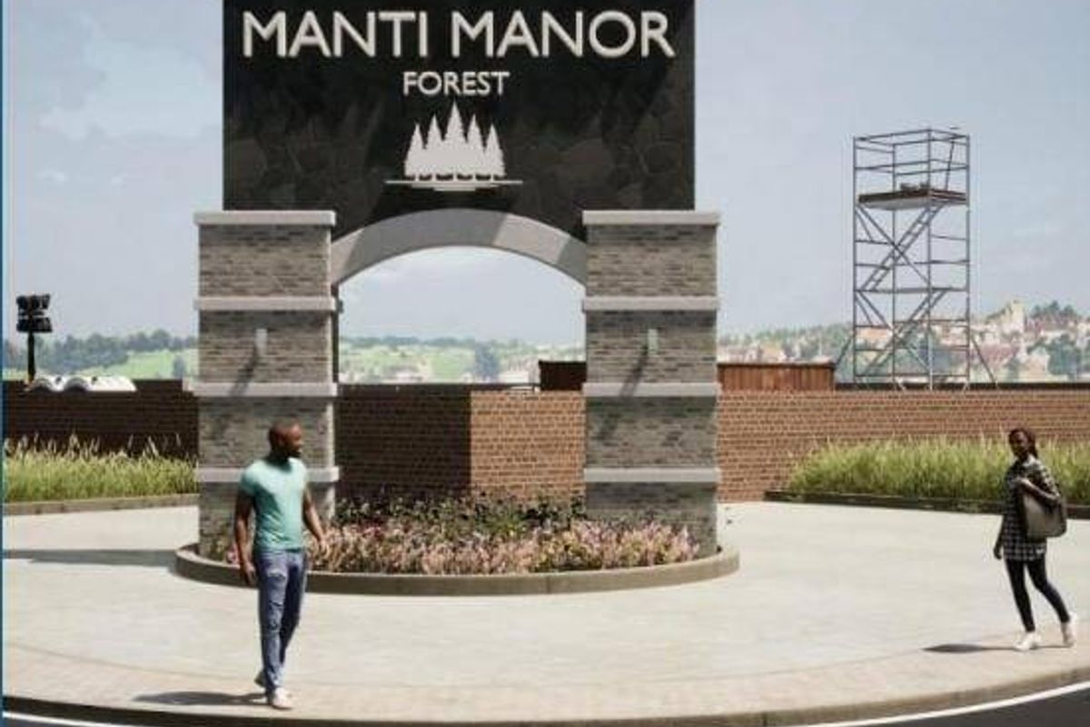A modern stone masonry entrance archway featuring the Manti Manor Forest signage, set within a landscaped residential estate entrance.