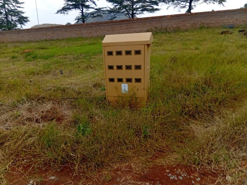 An outdoor electrical utility box situated on a grassy plot of land.