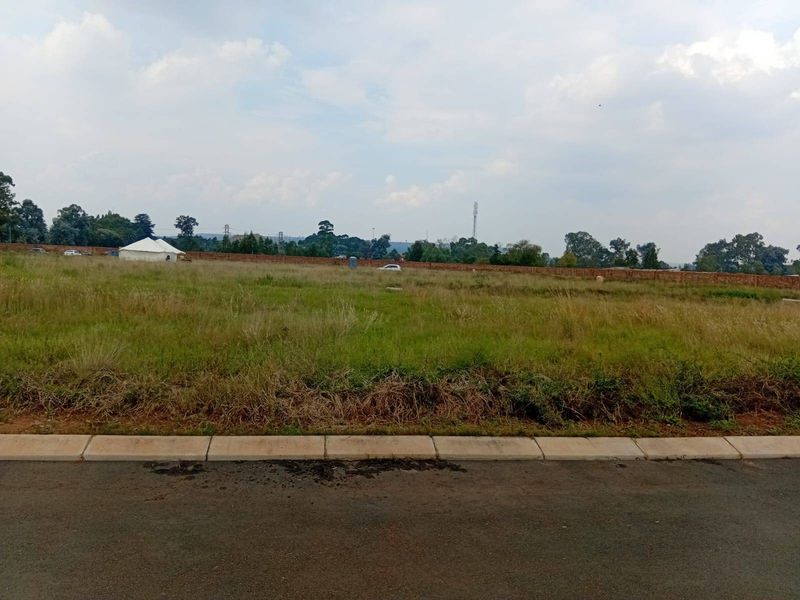 A vacant residential plot of land featuring a paved curb and perimeter brick wall, ready for development.