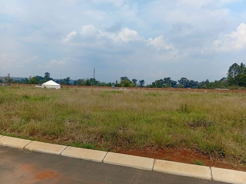 A vacant residential plot featuring established concrete kerbing and a perimeter brick wall, offering a clear space for future development.
